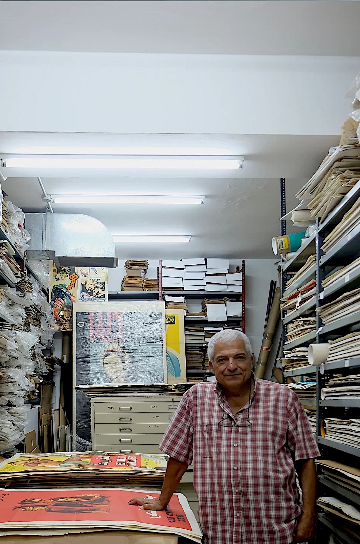 Dealer standing among shelves of prints in his archive