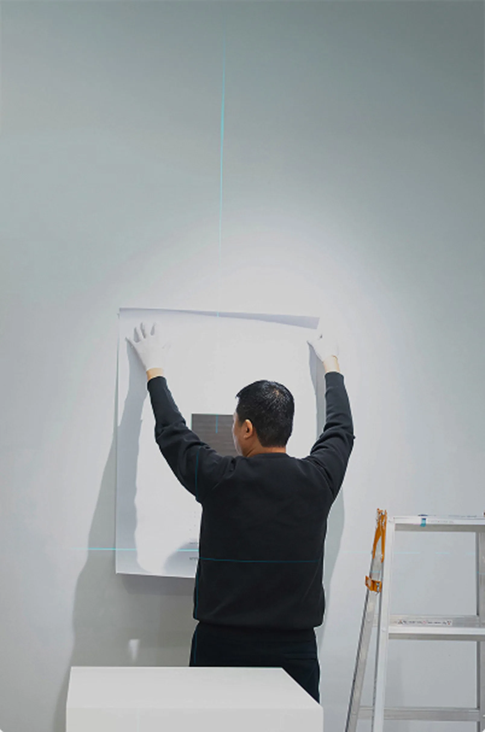 Art installer aligning a work on a gallery wall