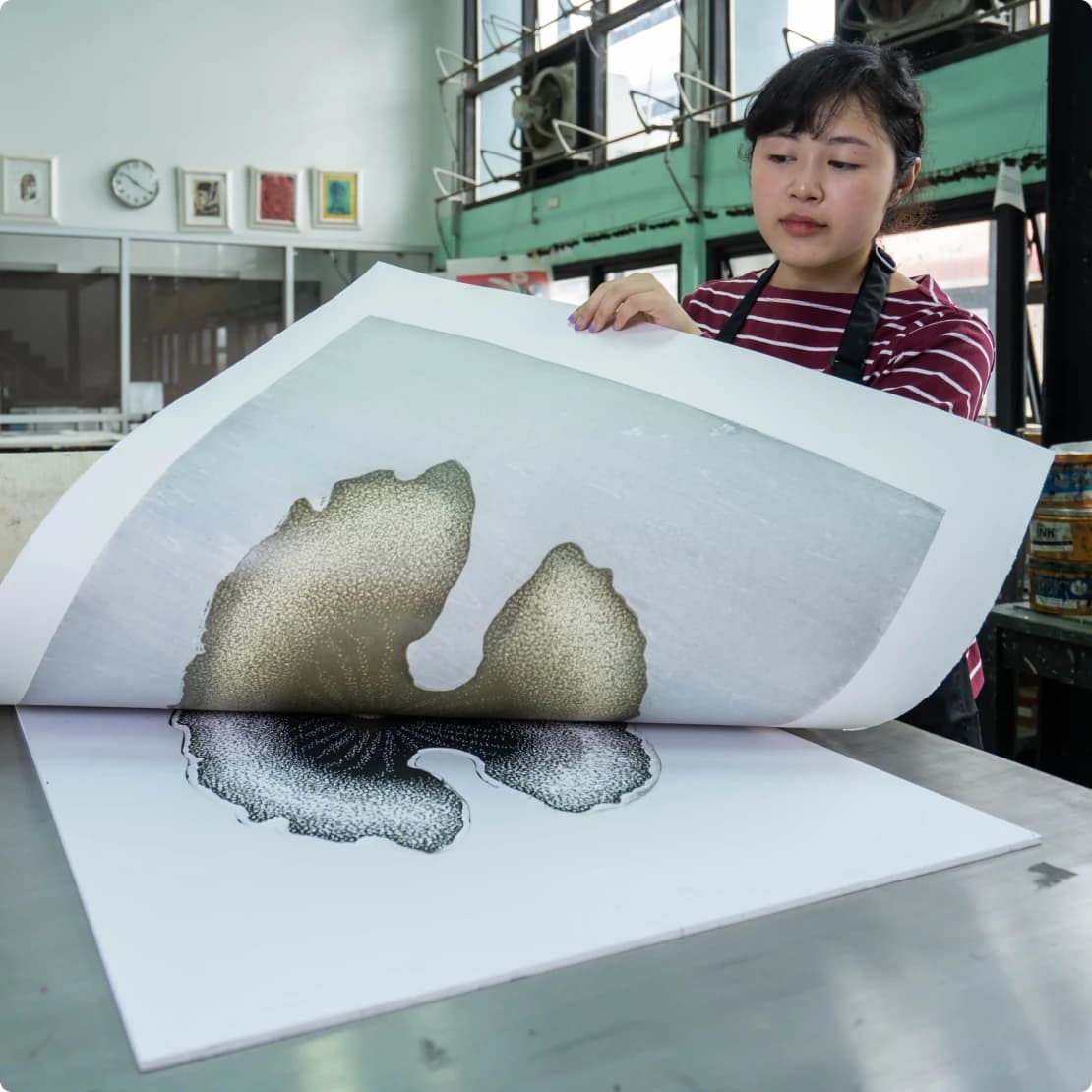 Printmaker lifting a freshly pulled print