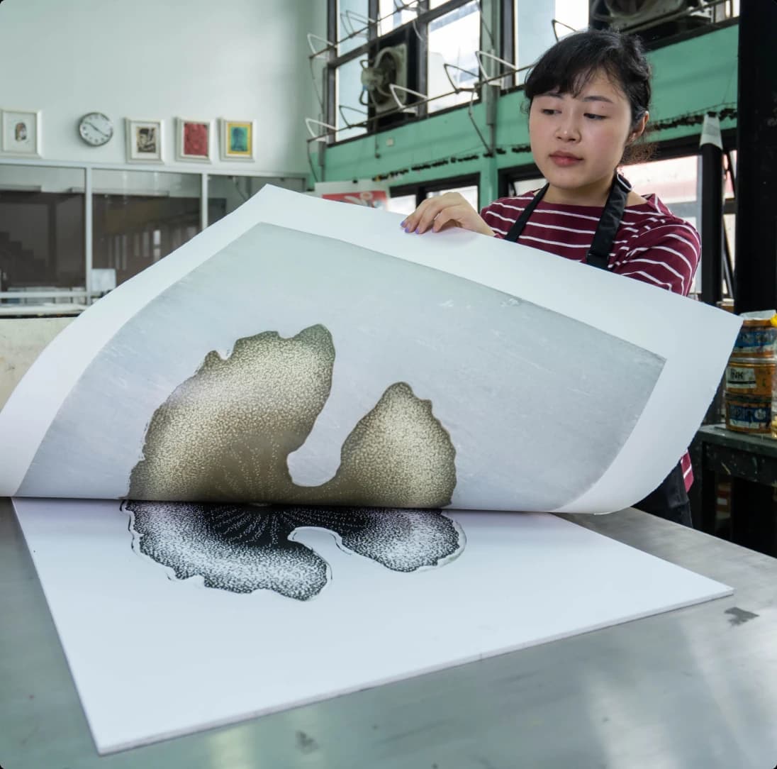 Printmaker lifting a freshly pulled print